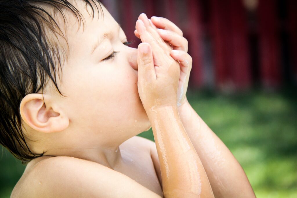 little child smelling baby skin care oil