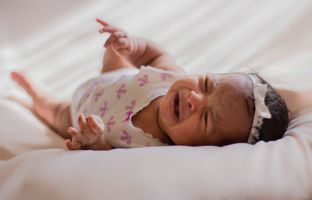 a crying baby lying in bed