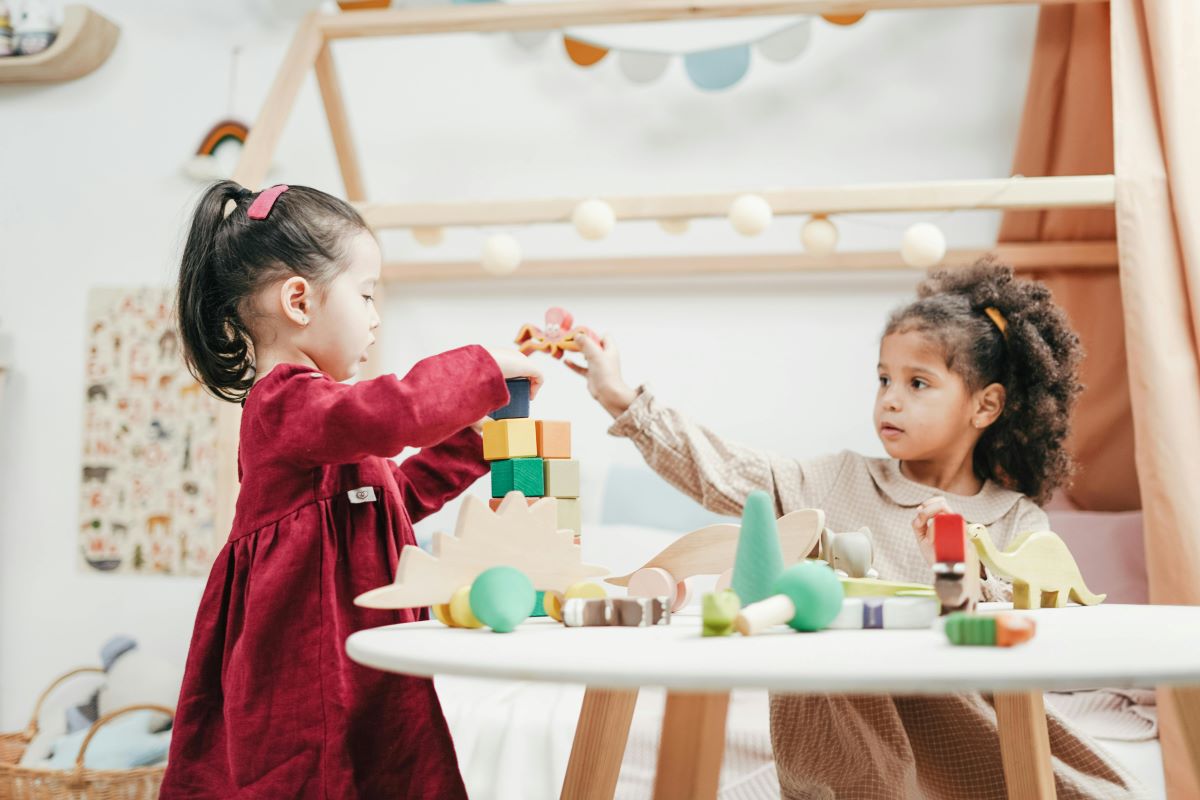 two little girls having a playtime using multi-colored blocks