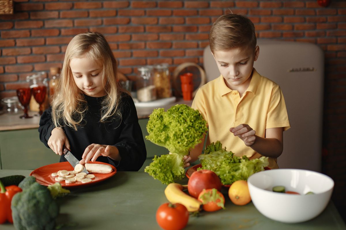 children cutting fruits with a knife and preparing veggies