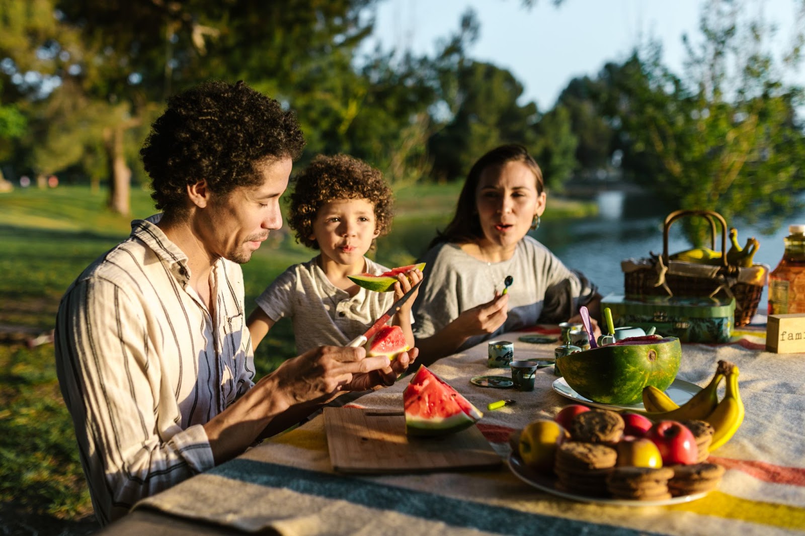 a family seated outside eating fruits