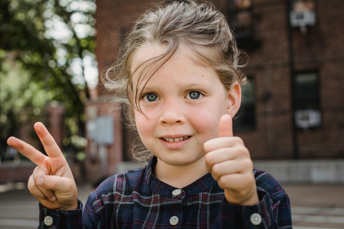  a girl showing a peace sign and thumb up