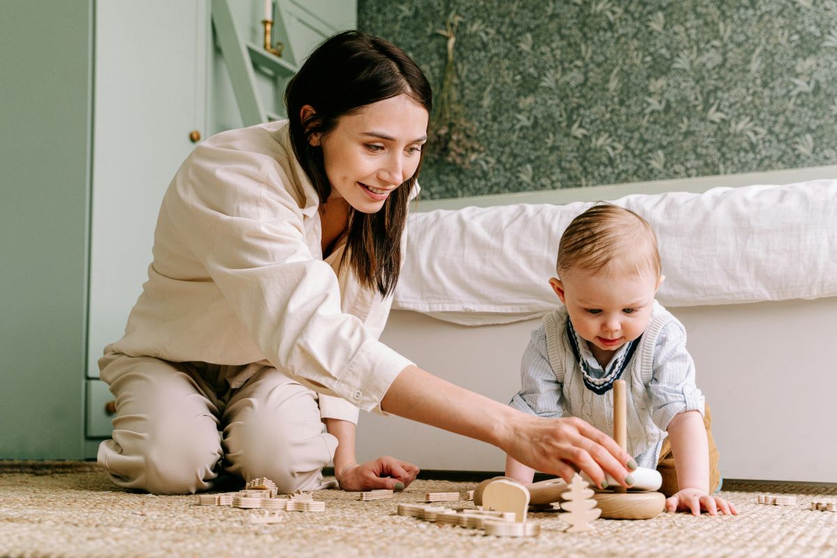 Mother and baby playing with wooden toy on the floor