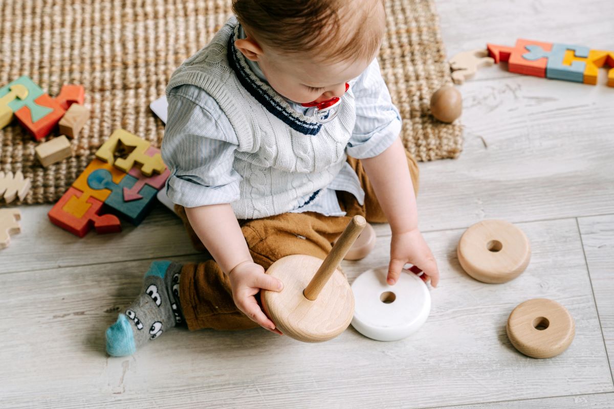 a boy playing with wooden blocks on the floor