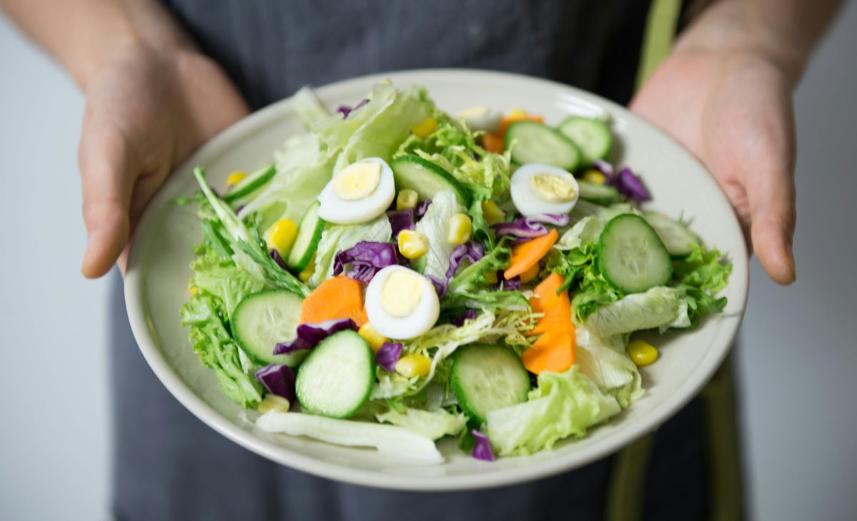 hands holding a plate full of mixed vegetables 