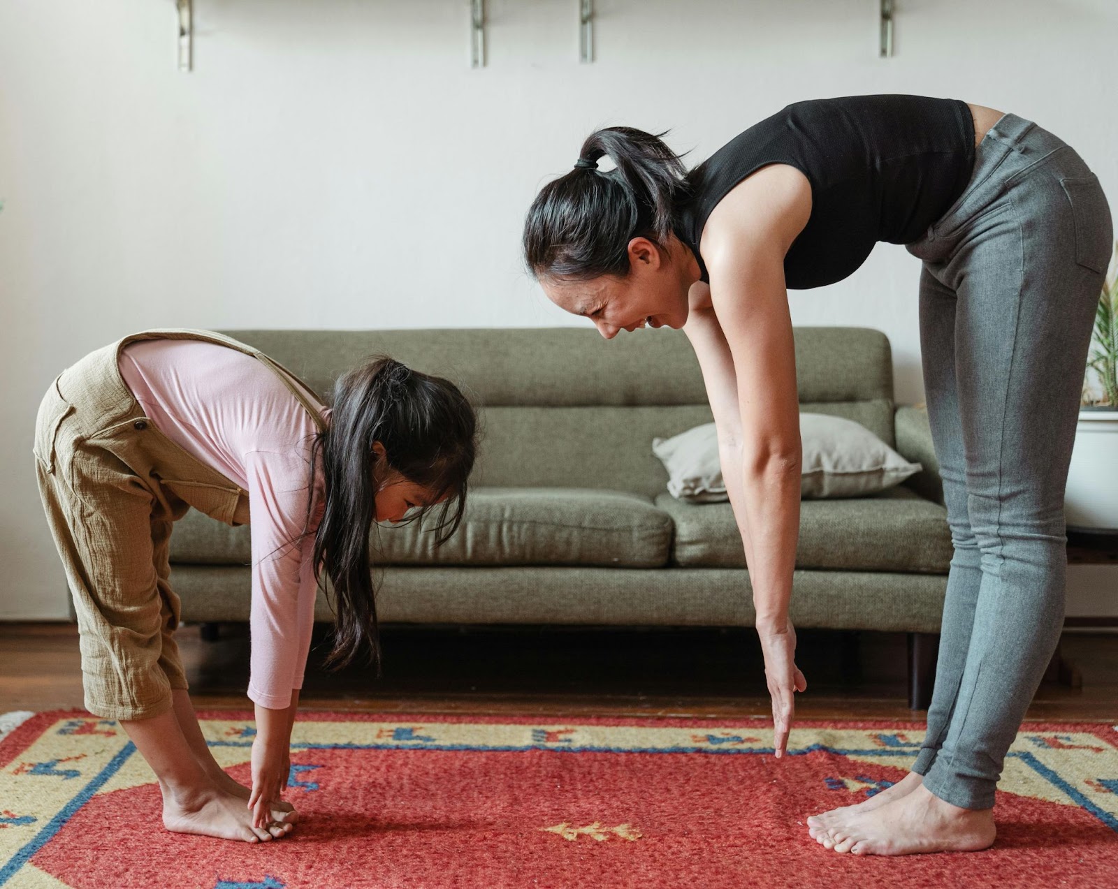 a smiling girl bending to exercise with her mom