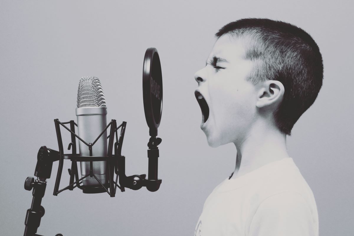 a boy singing on a microphone with a pop filter photo