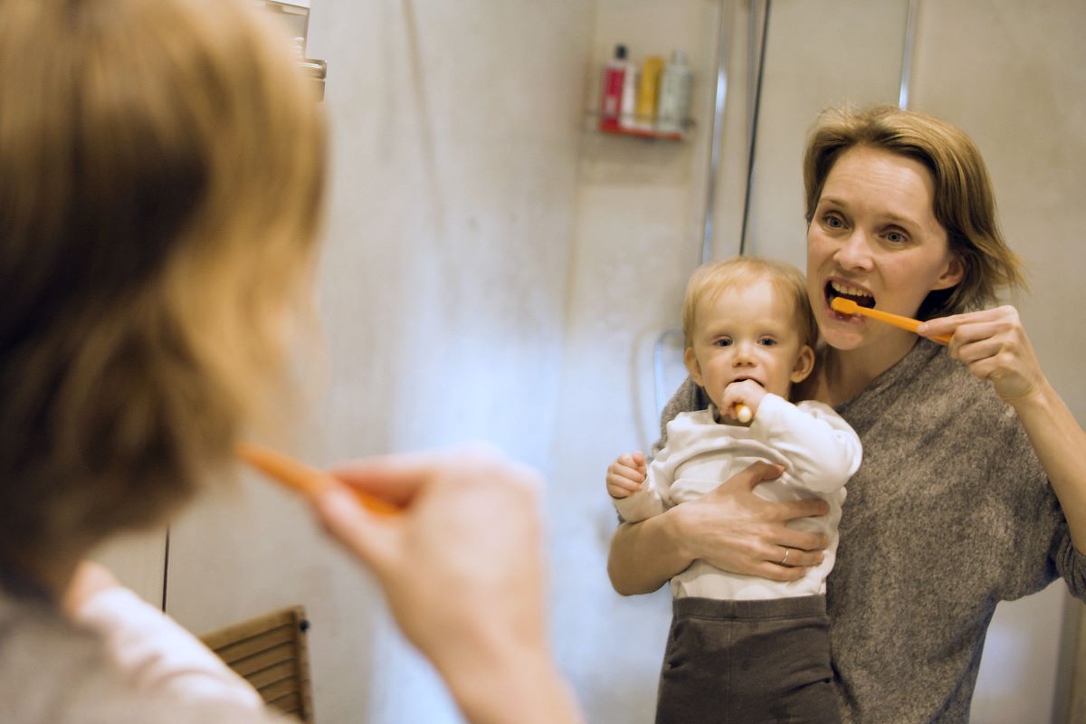 a woman and little boy brushing their teeth in front of a mirror