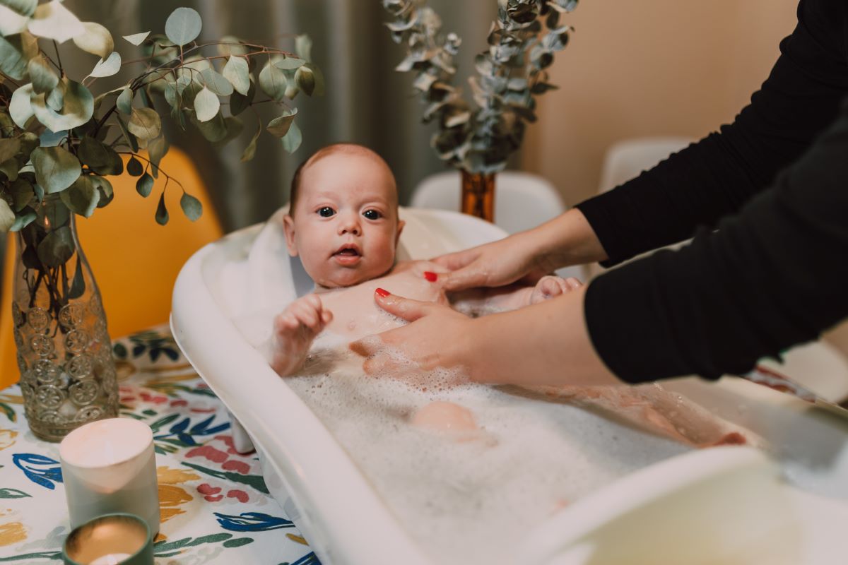 a lady bathing a baby in baby tub