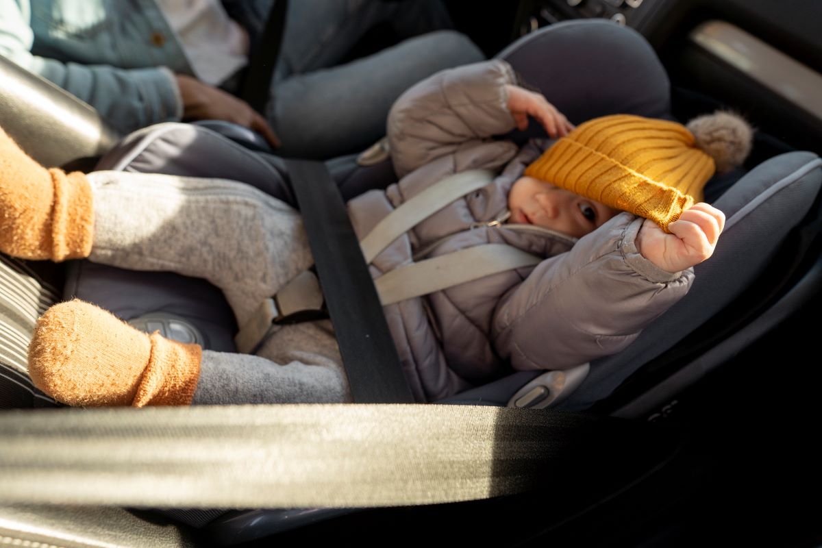 a baby lying on a rear-facing car seat