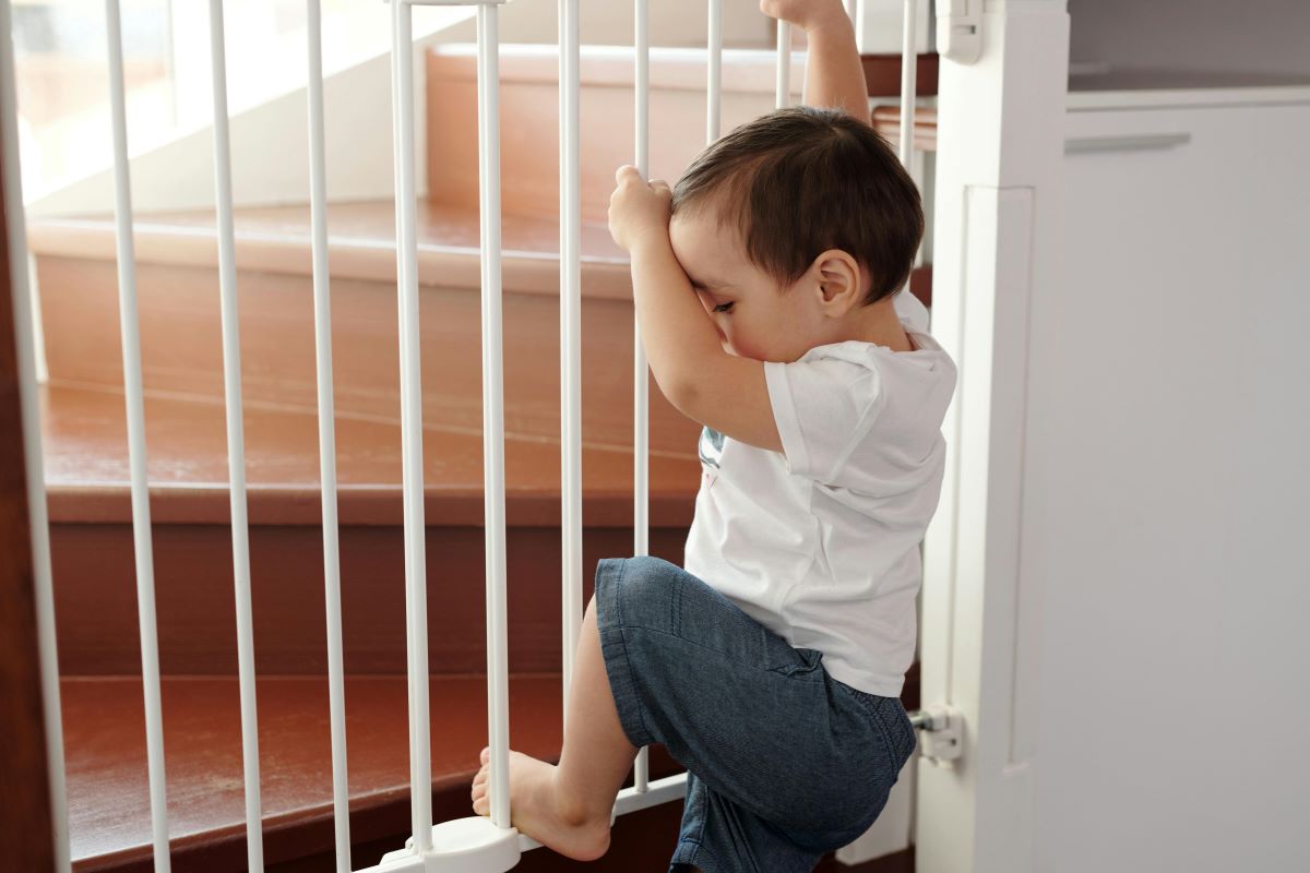 a little boy trying to climb a stairway gate