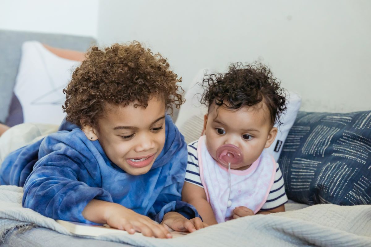 two children lying on their stomachs on a cozy bed