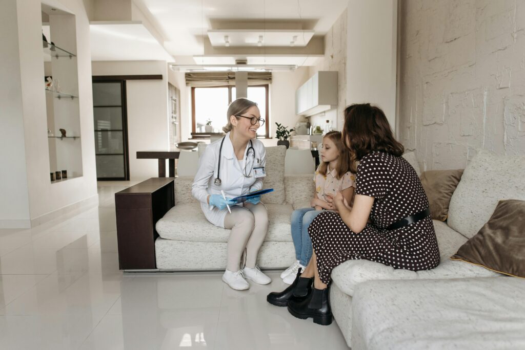 a doctor, little girl and her mom sitting on a sofa